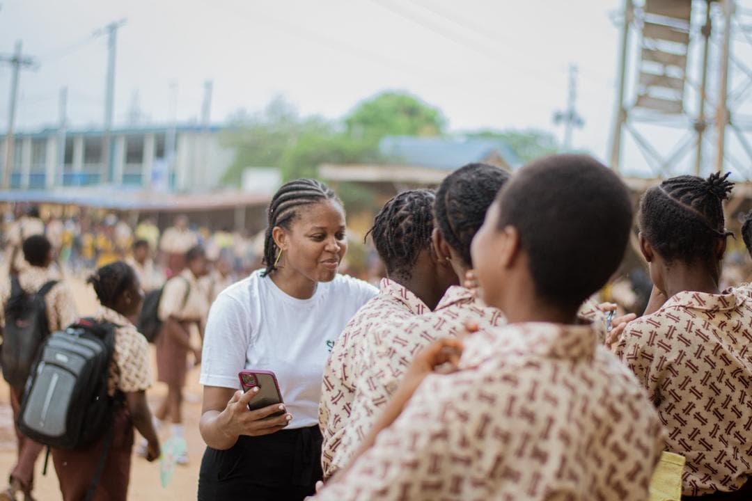 A volunteer talking with students outside a school